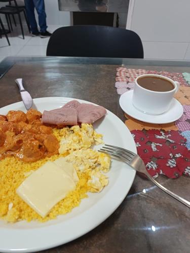 einen Teller Essen mit Gabel und eine Tasse Kaffee in der Unterkunft FLATS CAMPINA GRANDE - BSH FLATS - Melhor custo benefício in Campina Grande