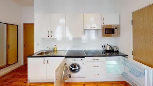 a white kitchen with a sink and a dishwasher at Comfortable Studio in City Centre Nottingham in Nottingham