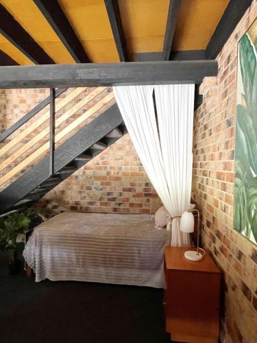 a bedroom with a bed in a brick wall at The Loft in South West Rocks