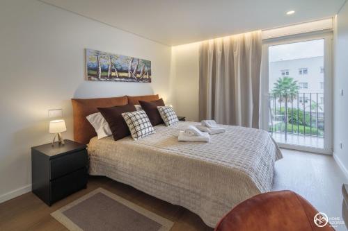a bedroom with a bed and a large window at Home Azores - Coliseu Residences in Ponta Delgada