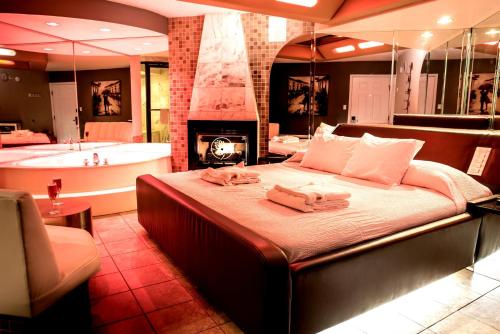 a bedroom with a bed with a fireplace and a tub at Essence Suites in Orland Park