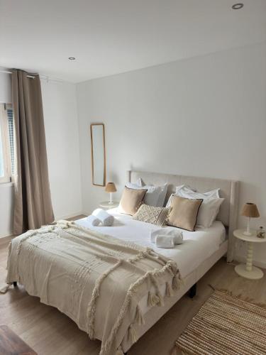 a white bedroom with a large white bed with pillows at Coastal Sands Azores in Ribeira Grande