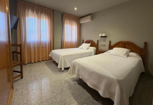 a hotel room with two beds and a television at Casa Santos in Albalate de Cinca