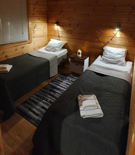 two beds in a room with wooden walls at Orakoski Camping in Sodankylä
