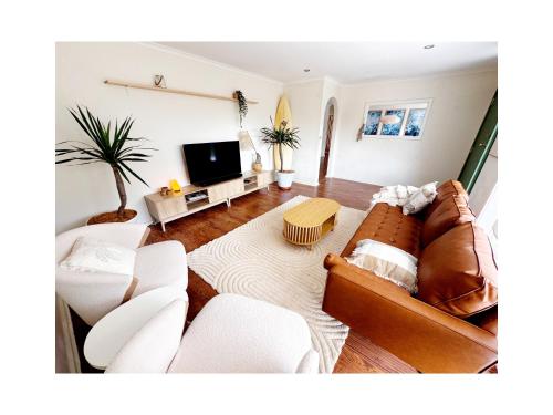 a living room with a couch and a tv at Walk to Beach - Coastal Beach House Retreat in Port Willunga