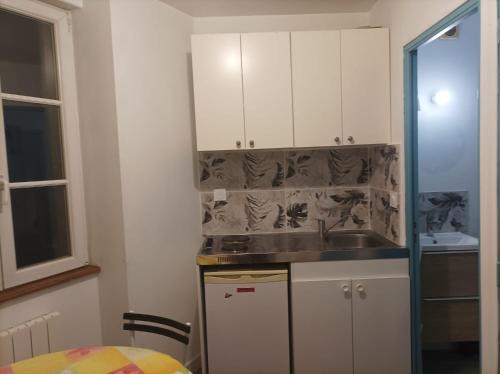 a kitchen with white cabinets and a sink at Le studio du cinéma in Évron