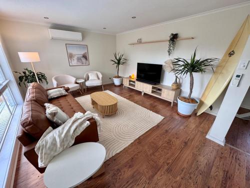 a living room with a couch and a tv at Walk to Beach - Coastal Beach House Retreat in Port Willunga