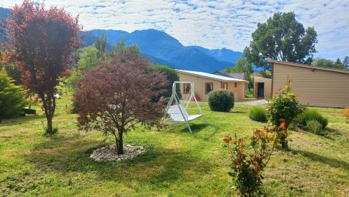 a house with a yard with a swing at Cabañas Mi Viejo in El Hoyo