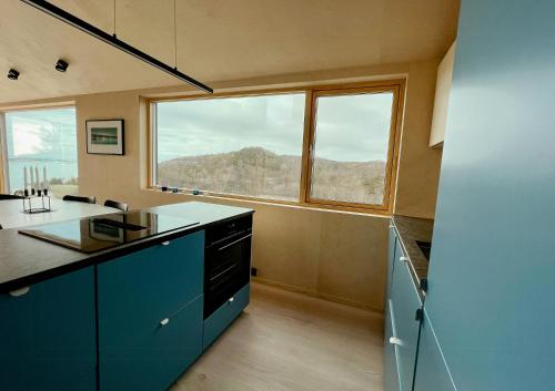 a kitchen with blue cabinets and a large window at Architect Drawn Cabin With Sea View At Stokkøy in Hosen