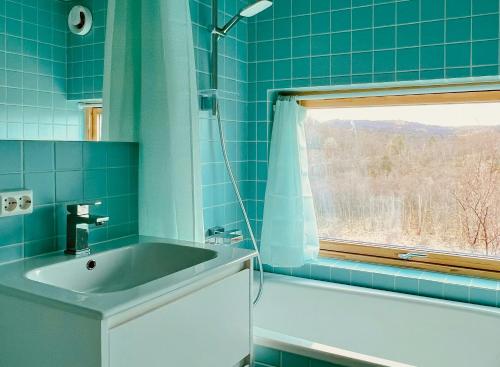 a blue tiled bathroom with a sink and a window at Architect Drawn Cabin With Sea View At Stokkøy in Hosen