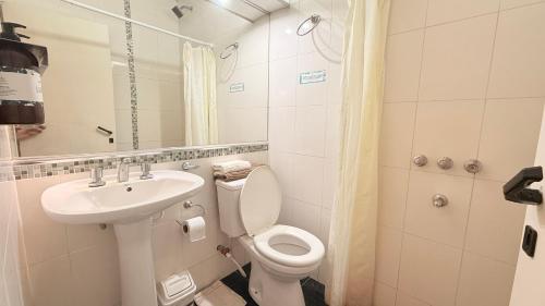 a white bathroom with a toilet and a sink at G8 Hermoso Monoambiente con Cochera 2 huéspedes in Villa Ángela