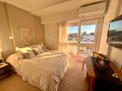 una camera da letto con un letto e una grande finestra di Apartamento Torreón Cerca del mar y Güemes a Mar del Plata