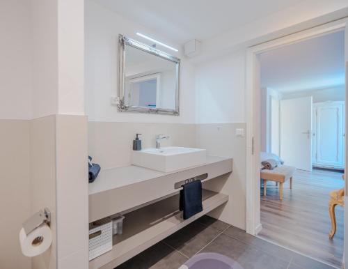 een witte badkamer met een wastafel en een spiegel bij Mountain Residence in Kandersteg