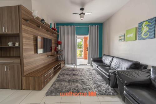 a living room with a black leather couch and a television at Apto em Bertioga a beira mar com varanda gourmet in Ilha Monte Pascoal