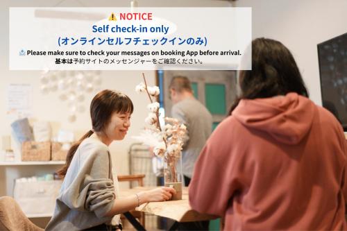 a woman sitting at a table with a vase of flowers at hostel Ini kobe l Self Cozy Stay in Kobe