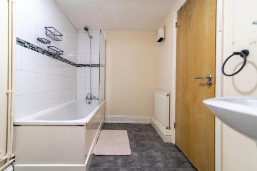 a bathroom with a white tub and a sink at Charming 3 Bed Flat by Harbour in Folkestone