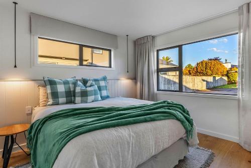 ein Schlafzimmer mit einem Bett und einem großen Fenster in der Unterkunft Memories - stunning relaxation near lake with private hot tub in Taupo Airport