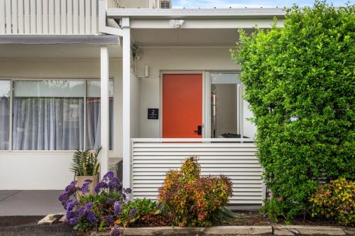 an orange front door of a house with flowers at Newly Renovated Geelong Serviced Apartments by Short & Long Stays in Geelong