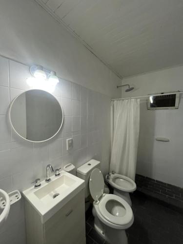 a bathroom with a sink and a toilet and a mirror at La Casita de los Cholis in Colón
