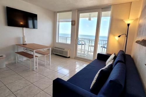 a living room with a blue couch and a table at Direct Oceanfront 1BR Balcony King Bed Beach Access in Daytona Beach