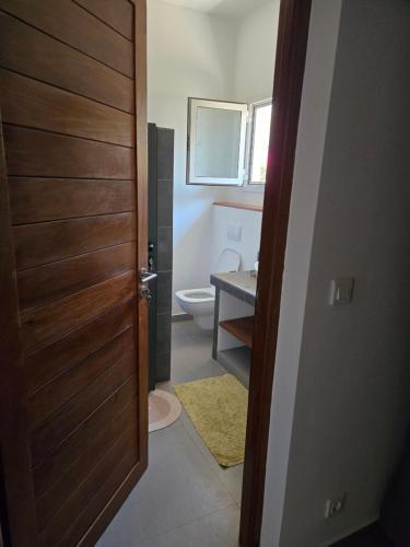 a bathroom with a toilet and a wooden door at Villa d'évasion proche de la plage in Boukot Ouolof