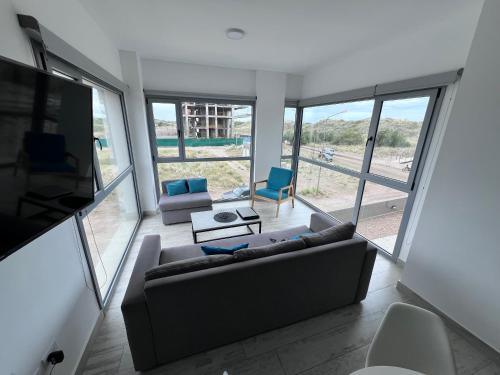 ein Wohnzimmer mit Sofa, Stühlen und Fenstern in der Unterkunft Torres Al Mar in Monte Hermoso