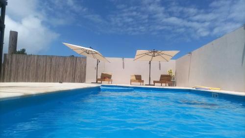 a swimming pool with two umbrellas and two chairs at Cabañas Batavi in Punta Del Diablo