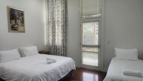 een slaapkamer met twee bedden en een raam bij Mary MacKillop Spirituality Centre Central Coast in Kincumber South