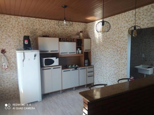 Cianorteにあるcasa aconchegante para seu descansoのキッチン(冷蔵庫、カウンター、椅子付)