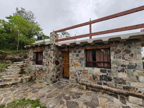 an old stone house with a wooden door at Atardecer in Tzicuilán