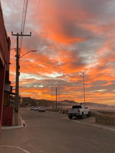 a car parked on the side of a street with a sunset at Pousada o pescador in Icapuí