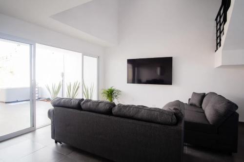 un salon avec un canapé et une télévision à écran plat dans l'établissement Modern House with Jacuzzi & Grill 3BR, à La Playita
