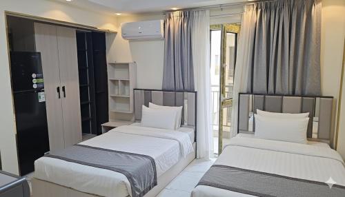 two beds in a small room with windows at living Hotel in 6th Of October