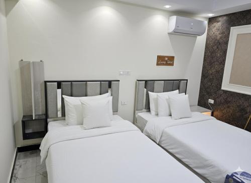 two beds in a hotel room with white sheets at living Hotel in 6th Of October