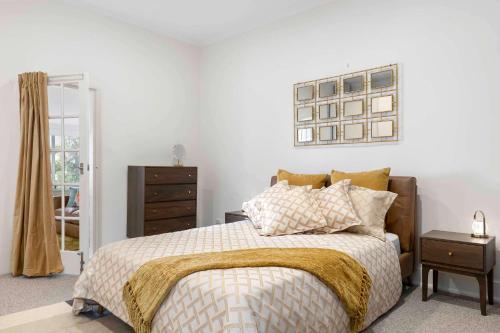 a bedroom with a bed and a dresser and a mirror at The Golden Key Henley Beach in Henley Beach South