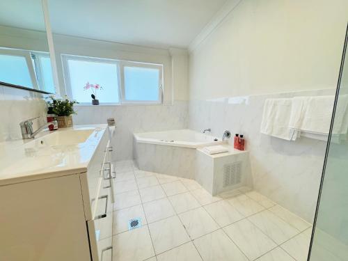 un bagno bianco con vasca e lavandino di Tranquil Suites in Heart of Leura 3 Minutes to Shops a Leura