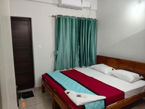 a bedroom with a bed with a green curtain at ElShium Homes in Cochin