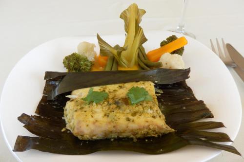 un plato de comida con un trozo de pescado y verduras en Dutchess Hotel and Restaurant, en Fort Portal