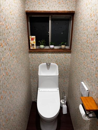 a bathroom with a white toilet with a window at sneaky peaks in Hakuba