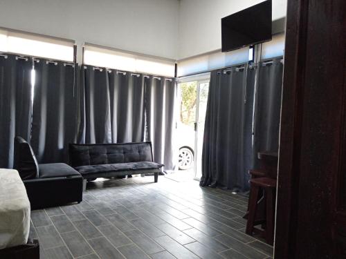 sala de estar con cortinas negras y sofá en Pino Lodge, Río Celeste, en Upala
