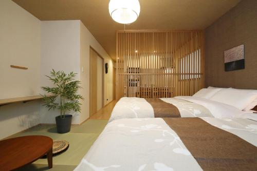 a bedroom with two beds and a potted plant at Kamon Inn Uji 2-D in Uji
