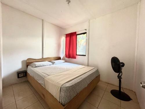 a bedroom with a bed and a red window at Kalunay Hostel - Breakfast included in Puerto Viejo