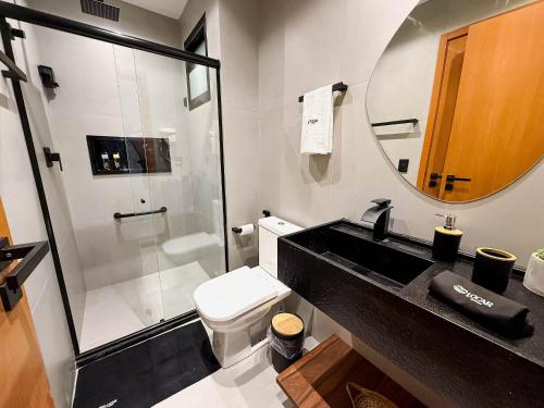 une salle de bain avec un lavabo, des toilettes et un miroir dans l'établissement Flat premium no Naay Villas Boutique para 8 pessoas, à Tatuamunha