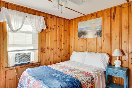 Schlafzimmer mit Holzwänden und einem Bett mit Fenster in der Unterkunft 1 Block to Humarock Beach Pet-Friendly Cottage in Fourth Cliff