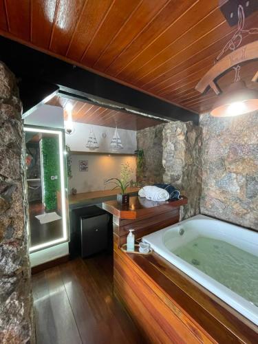 a bathroom with a large tub and a sink at Pousada Vista Grega in Arraial do Cabo