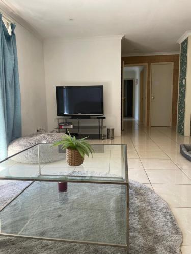 a living room with a tv and a glass table at Close to shops & airport in Perth