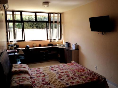 ein Schlafzimmer mit Bett, Schreibtisch und Fenster in der Unterkunft Casa em Olinda com piscina para o carnaval in Olinda
