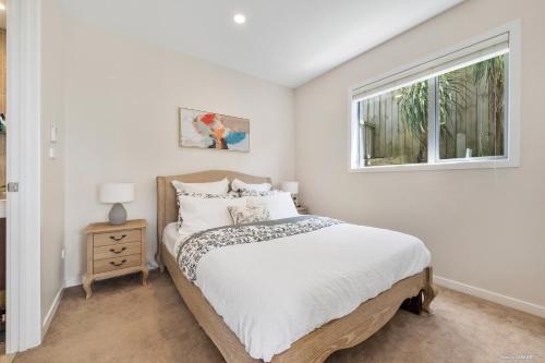 a white bedroom with a bed and a window at Blue Horizon in Auckland