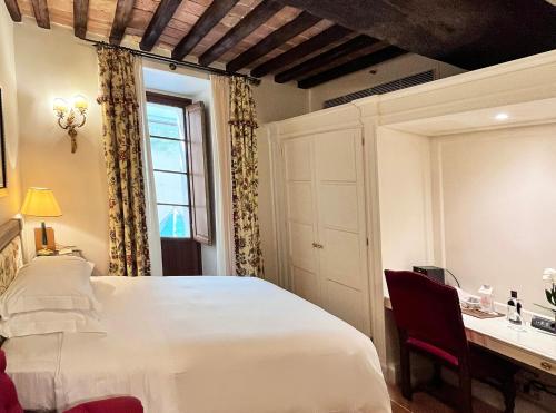 a bedroom with a bed and a desk and a window at Grand Hotel Continental Siena - Starhotels Collezione in Siena