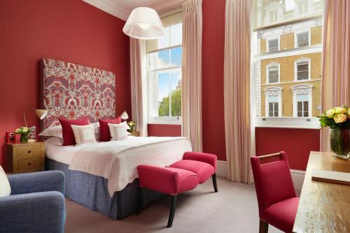 a red bedroom with a bed and two red chairs at The Pelham London - Starhotels Collezione in London